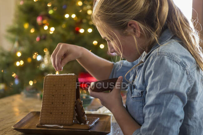 11 - річна дівчинка будує вдома імбирний хлібний будинок. — стокове фото