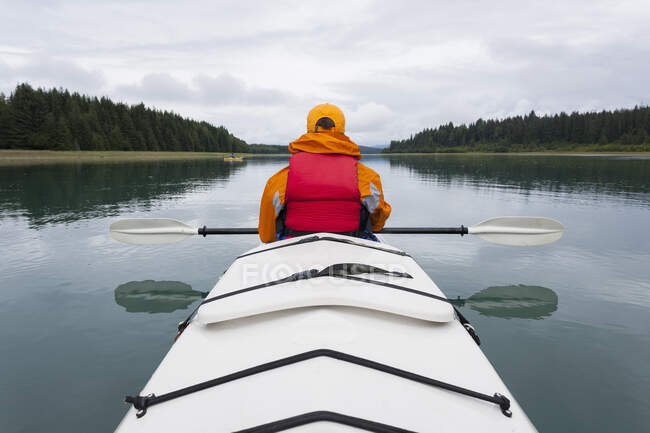 Woman sea kayaking calm water of an inlet in a national park. — Stock Photo