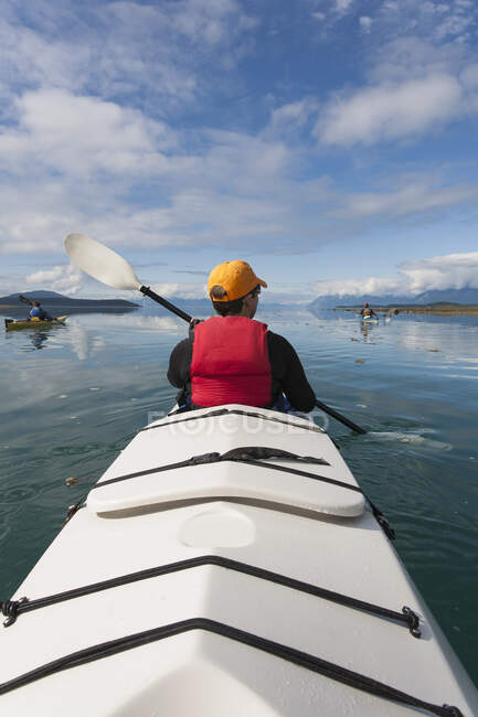 Un pequeño grupo de personas kayaks en aguas cristalinas de una ensenada en la costa de Alaska. - foto de stock