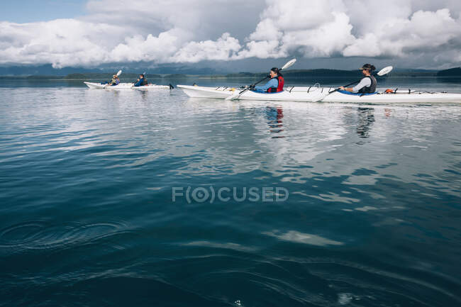 Kayakistes de mer pagayant dans les eaux vierges d'un bras de mer sur la côte de l'Alaska. — Photo de stock