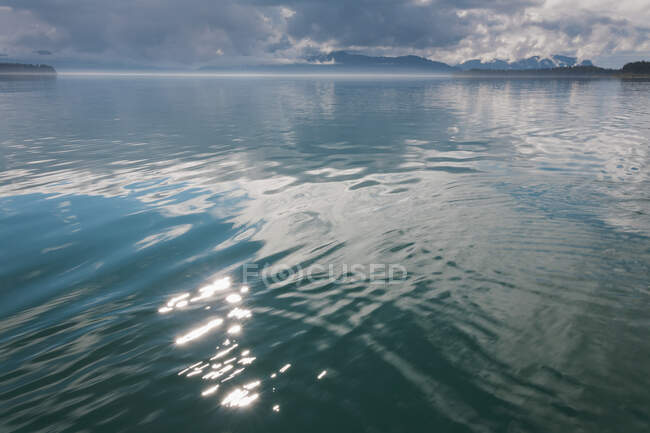 Luz solar reflejando en las tranquilas aguas de Muir Inlet al atardecer, Glacier Bay National Park, Alaska - foto de stock