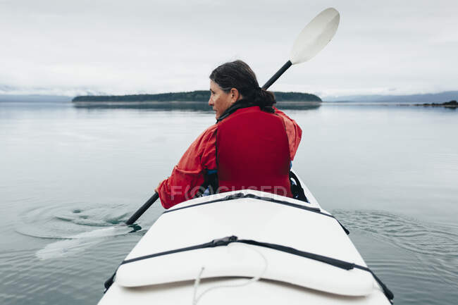 A middle-aged woman paddles sea kayak in the pristine waters of Muir Inlet, Glacier Bay National Park and Preserve, Alaska — Stock Photo