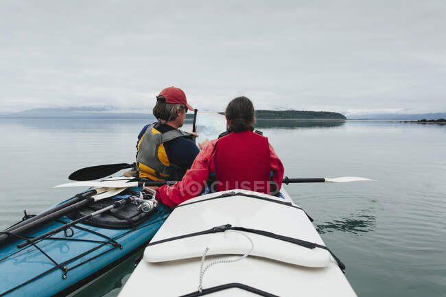 Kayakistas de mar mirando carta náutica y mapa, una ensenada en la costa de Alaska. - foto de stock