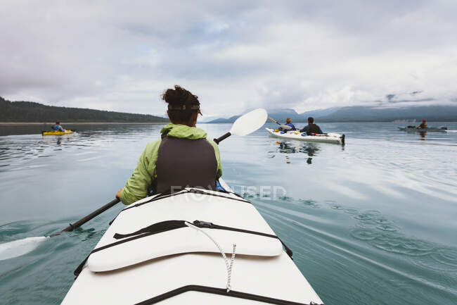 Gruppo di kayaker da mare che remano nelle acque incontaminate di una insenatura sulla costa dell'Alaska. — Foto stock
