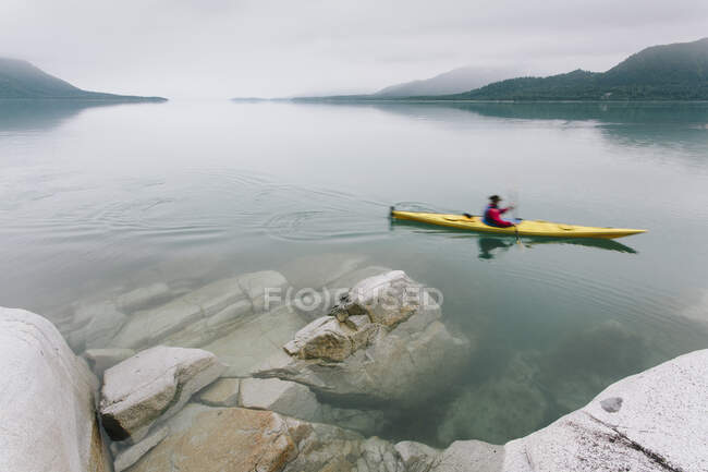 Femmina kayaker mare pagaiare acqua incontaminata di Muir Inlet, cielo coperto in lontananza, Glacier Bay National Park, Alaska — Foto stock