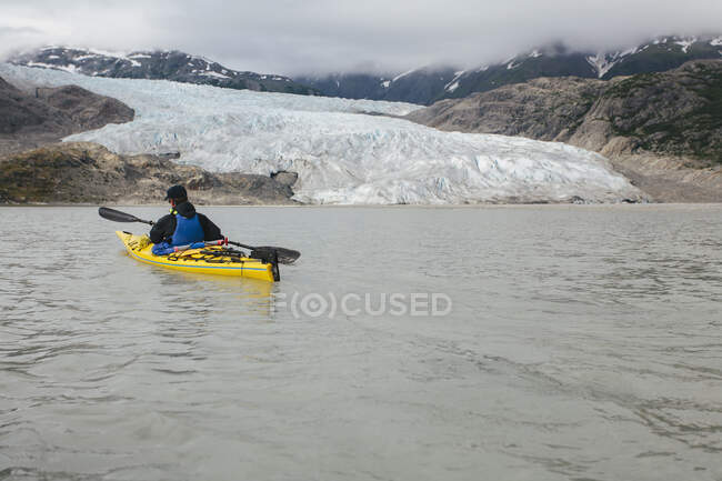 A sea kayaker approaches a glacier terminus, where the ice meets the sea. — Stock Photo