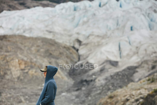 Uma jovem mulher de pé no final de uma geleira em uma costa rochosa no Alasca. — Fotografia de Stock