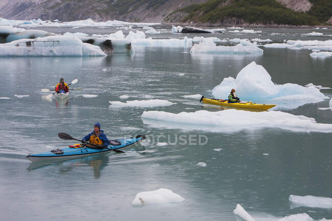 Kayakistas de mar remando en una laguna glaciar en una terminal glaciar en la costa de Alaska - foto de stock