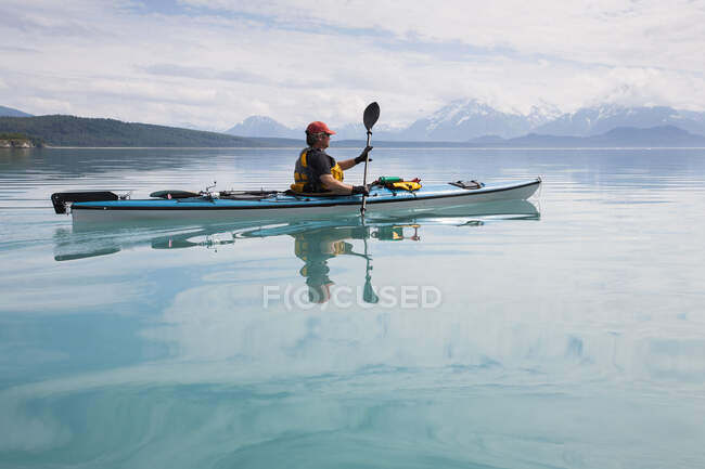 Hombre kayak de mar aguas tranquilas de una ensenada en un parque nacional. - foto de stock