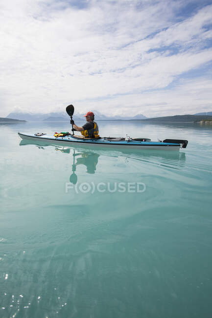 Hombre kayak de mar aguas tranquilas de una ensenada en un parque nacional. - foto de stock