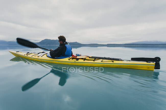 Hombre kayak de mar en una ensenada en la costa de Alaska. - foto de stock