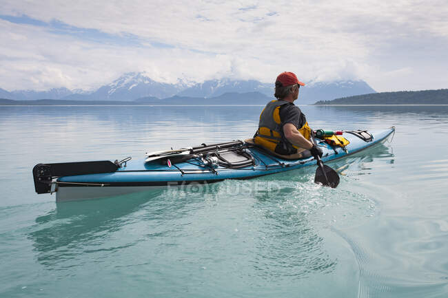 Man sea kayaking calm waters of an inlet in a national park. — Stock Photo