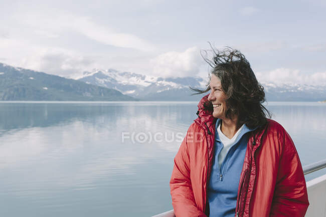 Mujer en la cubierta de un ferry en el agua con el pelo barrido por el viento. - foto de stock