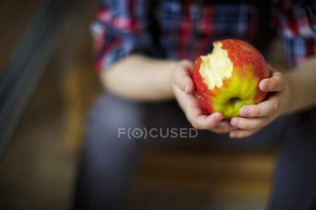 Close up of young child hands holding partly eaten apple — Stock Photo