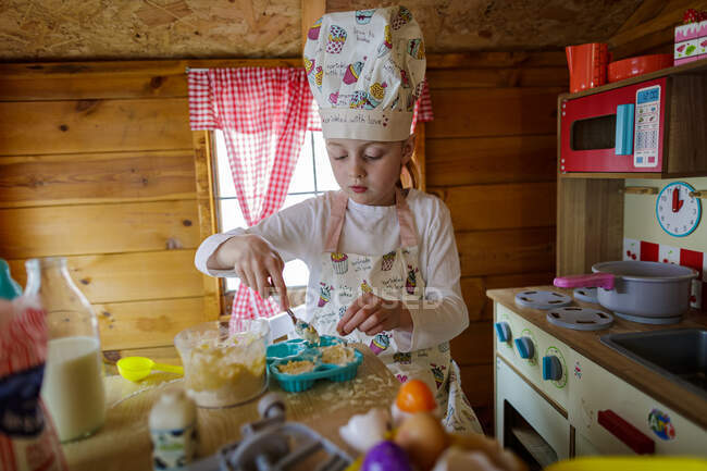 Jeune fille dans wendy maison prétendant cuisiner dans la cuisine — Photo de stock