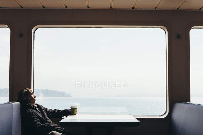 Ragazzo adolescente seduto sul traghetto, guardando fuori da una finestra — Foto stock