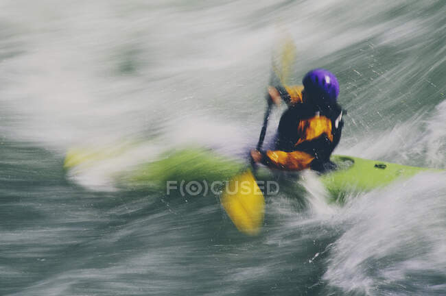 Kayak de aguas bravas remando y surfeando grandes rápidos en un río que fluye rápido - foto de stock