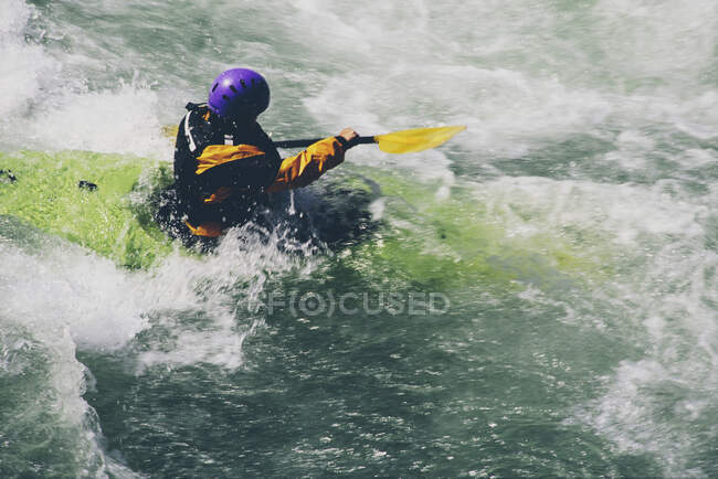 Kayakiste en eau vive pagayant de grands rapides sur une rivière qui coule rapidement — Photo de stock