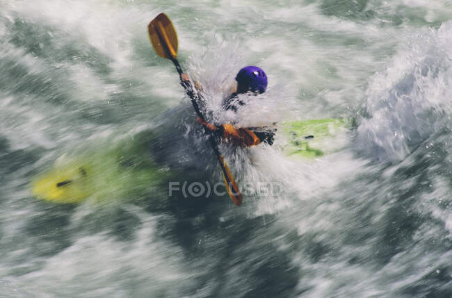 Kayakiste en eau vive pagayant de grands rapides sur une rivière qui coule rapidement — Photo de stock