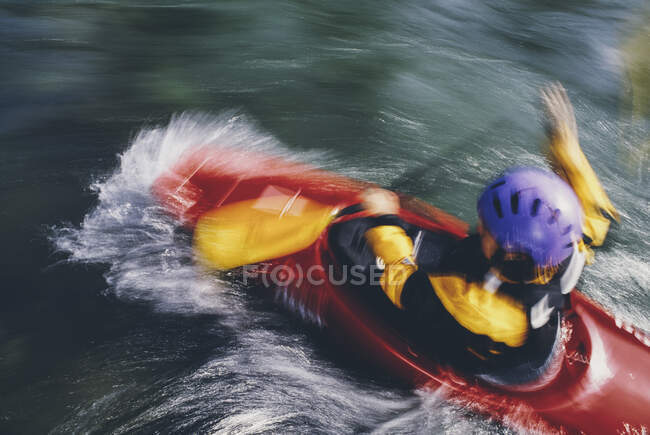 Longue exposition de kayakistes d'eau vive femelles pagayant sur des rapides et surfant sur une rivière à écoulement rapide. — Photo de stock