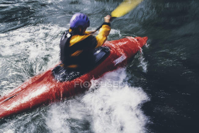 Larga exposición de kayakistas de aguas bravas hembras remando rápidos y surf en un río que fluye rápido. - foto de stock