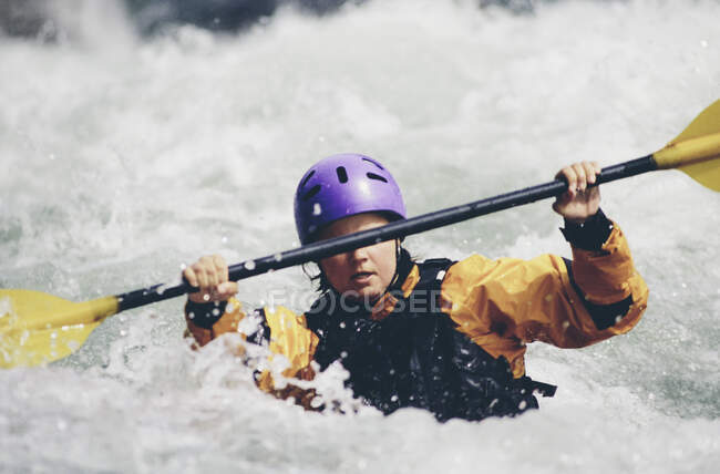 Kayak de aguas bravas hembra remando rápidos y surfear en un río que fluye rápido. - foto de stock