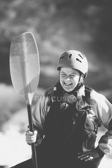 Female whitewater kayaker on a river bank holding a paddle. — Stock Photo