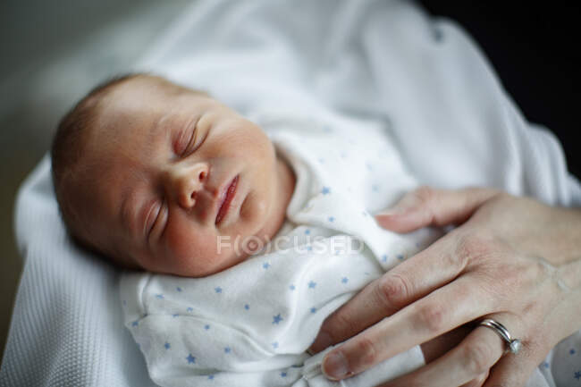 Sleeping baby with mother's hand resting on his chest — Stock Photo