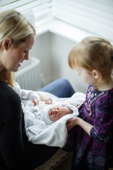 Мати і дочка доглядають за новонародженим — стокове фото