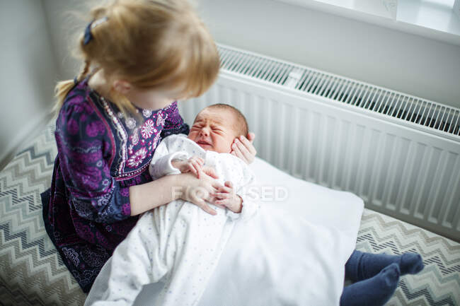 Young girl sitting holding newborn baby — Stock Photo