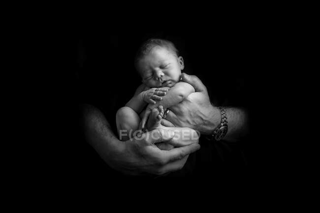 Bebê recém-nascido adormecido sendo mantido nas mãos do pai — Fotografia de Stock