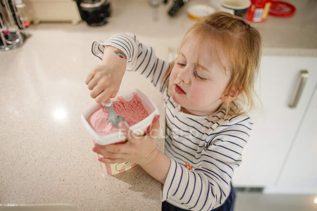 Young girl helping herself to ice cream — Stock Photo