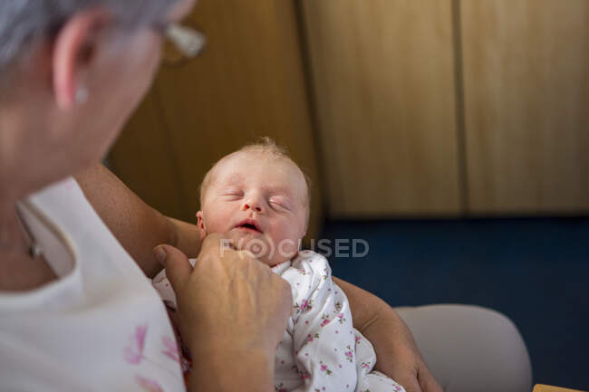 Una mujer sosteniendo un bebé recién nacido dormido - foto de stock