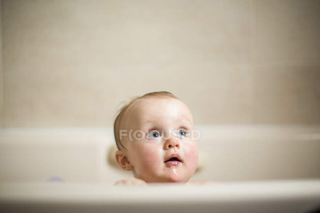 Cabeza del bebé mirando desde el baño - foto de stock