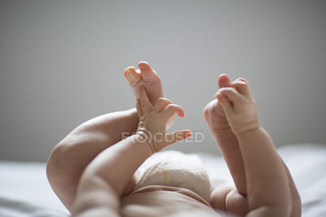 Plan recadré des jambes et des mains du bébé couché sur le dos — Photo de stock
