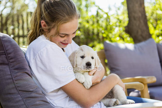 Adolescente chica holding golden retriever cachorro - foto de stock