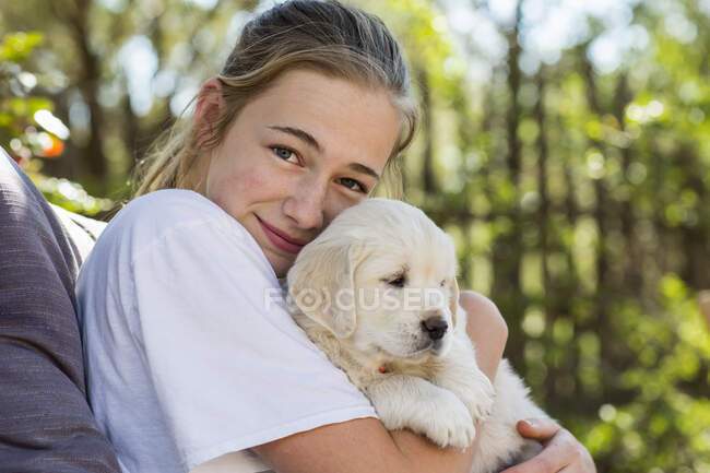 Adolescent fille tenant golden retriever chiot — Photo de stock
