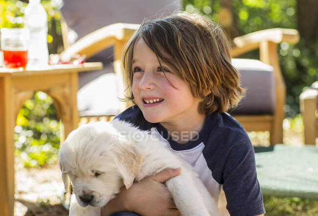 6 ano de idade menino segurando um Inglês golden retriever cachorro — Fotografia de Stock
