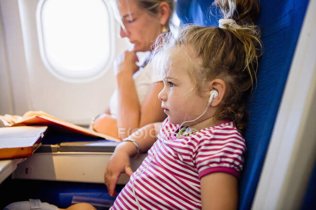 Young girl wearing headphones on airplane — Stock Photo