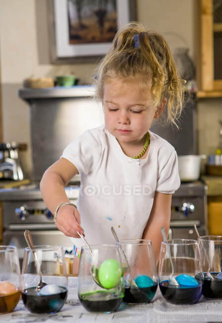 Niña de 3 años para colorear huevos de Pascua en casa - foto de stock