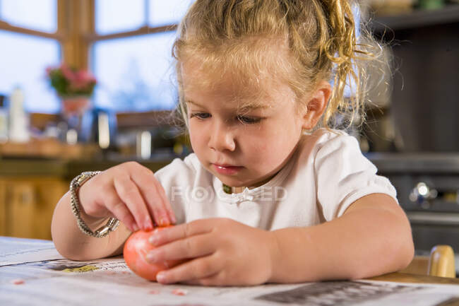 Трехлетняя девочка раскрашивает яйца в домашних условиях — стоковое фото