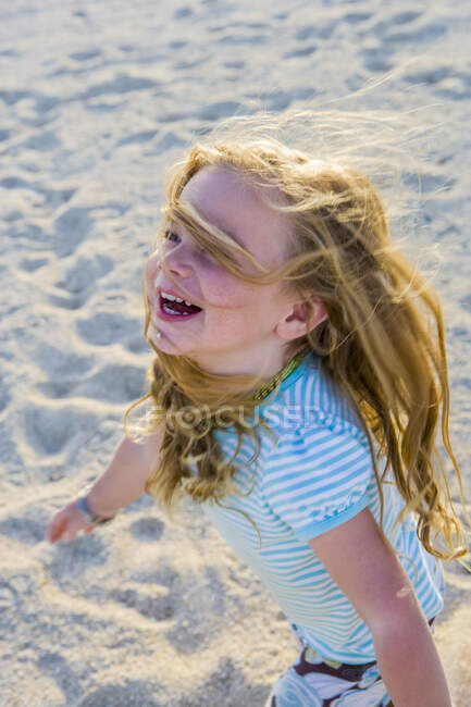 Riendo niña de 3 años corriendo en la arena - foto de stock