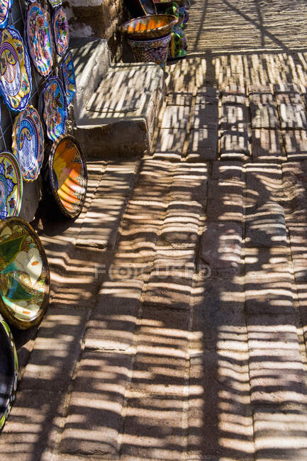 Sombras y patrones de sombra cayendo en un pavimento, tazones de cerámica en exhibición - foto de stock