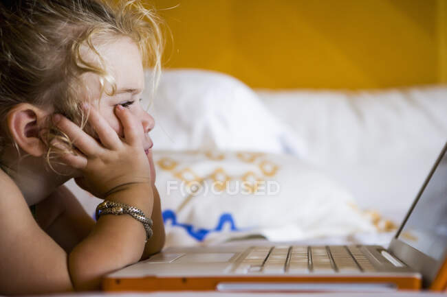 Menina de 3 anos olhando para laptop no quarto de hotel — Fotografia de Stock