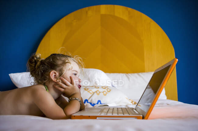 Трехлетняя девочка смотрит на ноутбук в гостиничном номере — стоковое фото