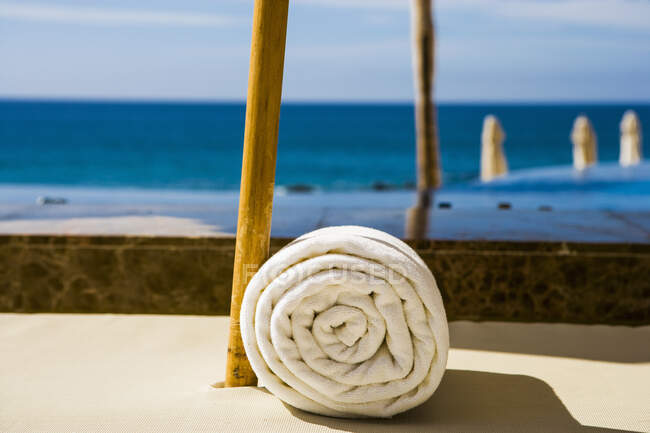 Vista ravvicinata di asciugamano bianco arrotolato su una terrazza con vista sulla spiaggia e sul mare. — Foto stock