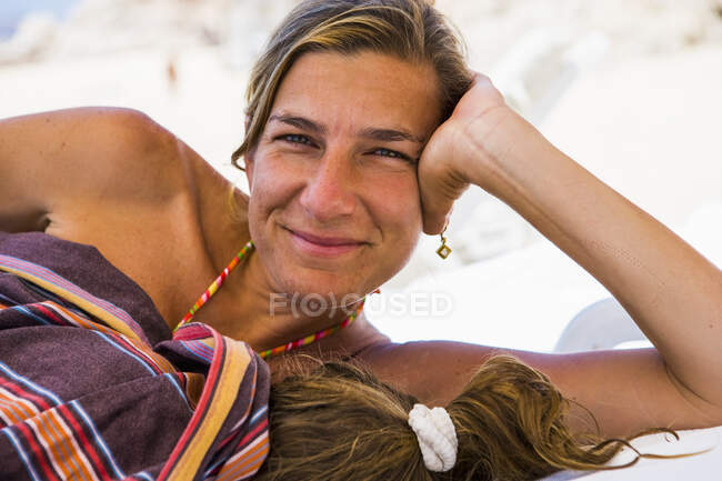Smiling woman resting with her young sleeping daughter, Cabo San Lucas, Mexico — Stock Photo