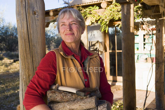 Доросла жінка вдома на своїй території в сільській місцевості з колодами. — стокове фото