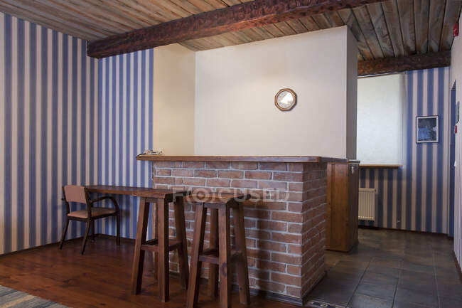 Un hotel con habitaciones antiguas de estilo retro, bar con dos taburetes de bar y papel pintado a rayas. - foto de stock