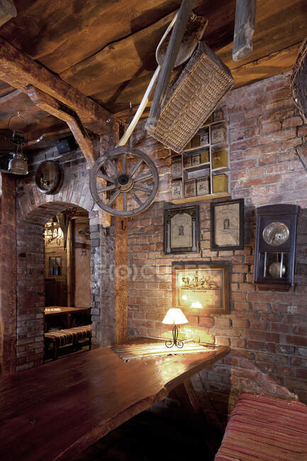 Bar with exposed brickwork and cart wheel, basket and old photographs at night — Stock Photo
